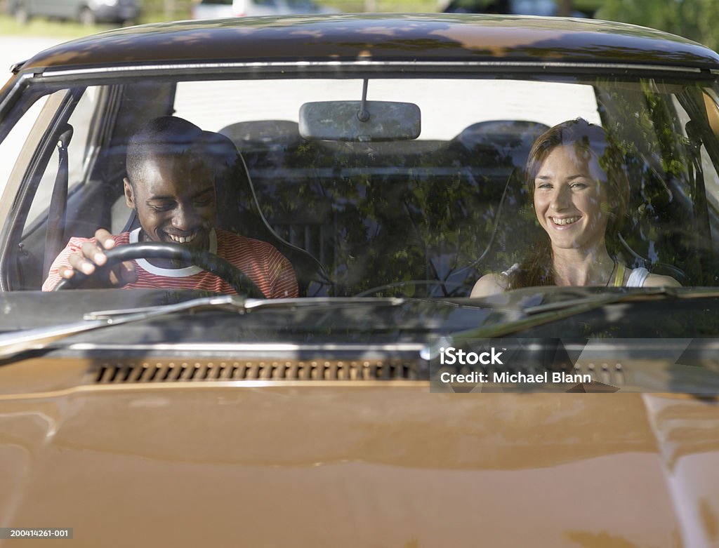 Jeune couple dans la voiture, souriant, vue sur le pare-brise - Photo de Pare-brise libre de droits