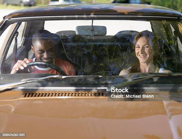 Photo libre de droit de Jeune Couple Dans La Voiture Souriant Vue Sur Le Parebrise banque d'images et plus d'images libres de droit de Pare-brise