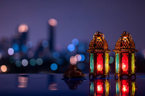 istock Two lanterns and small plate of dates fruit with night sky and city bokeh light background 2004198044