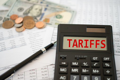 tariffs word on calculator screen with Invoice and export - Import declaration report.