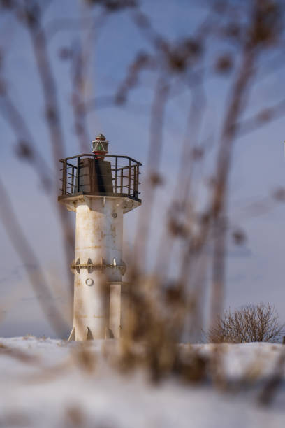 istock Old lighthouse in winter on a background of blue sky and bushes 2004227541