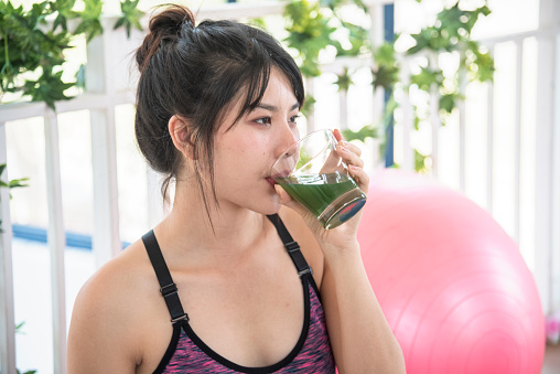Women hands holding smoothie detox green juice fresh fruit cool drinking. Asian women smile laugh drinking vegan vegetable cool wellness beverage. Female pouring celery juice drink cocktail glass