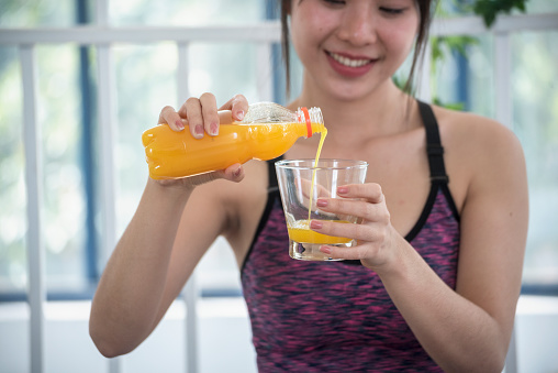 Asian women smile laugh look at camera health care home fitness lifestyle. Women hands holding cold orange juice fresh fruit cool drinking. Beautiful female pouring orange juice from cocktail bottle