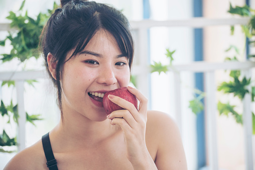 young asian woman eating Apple Healthy. Girl workout holding organic apple fruit healthy lifestyle. Wellness Asian women eat red apple smile face look at camera. Beauty health care lifestyle concept
