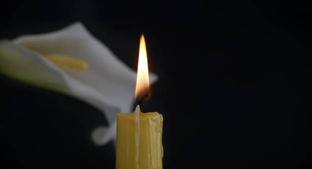 istock Burning wax candle and white calla lily flowers in darkness 2004241226