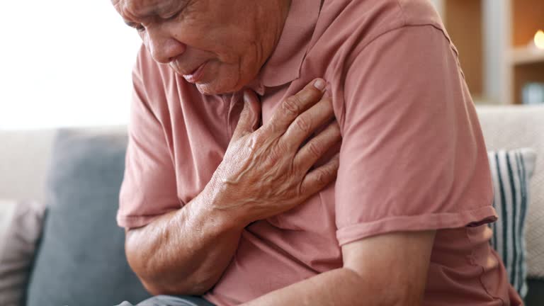 Senior man, heart attack and pain with emergency in home, massage chest and cardiovascular problems. Hands, mature person and coughing with lung disease, anxiety and living room with cardiac arrest