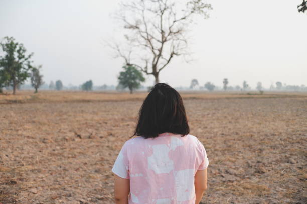 Rear View Of Boy Sitting On Barren Landscape