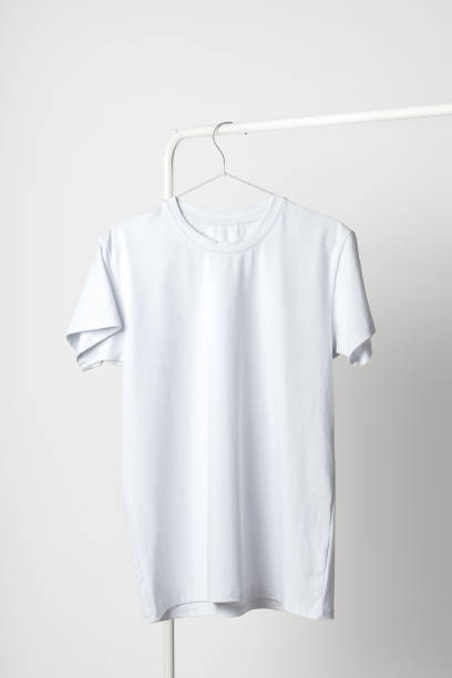 istock Plain white T-shirt hanging on hanger against white wall 2004276274