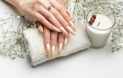 Manicured nails with pearlescent nail polish. The nails are covered with pearl gel polish on white background