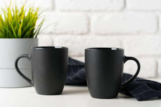 Two mugs on white table against brick wall background