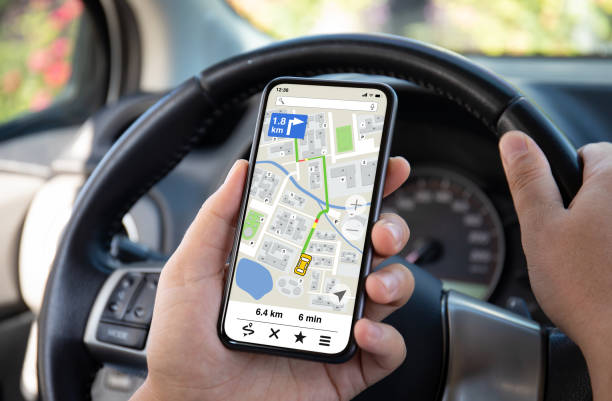 male hands hold phone with navigation application background of steering wheel in car