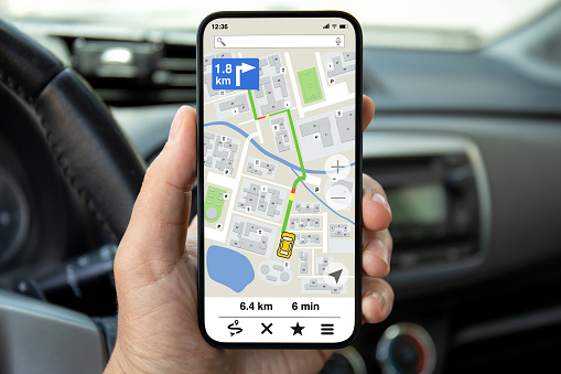 male hands hold phone with navigation application background of steering wheel in car