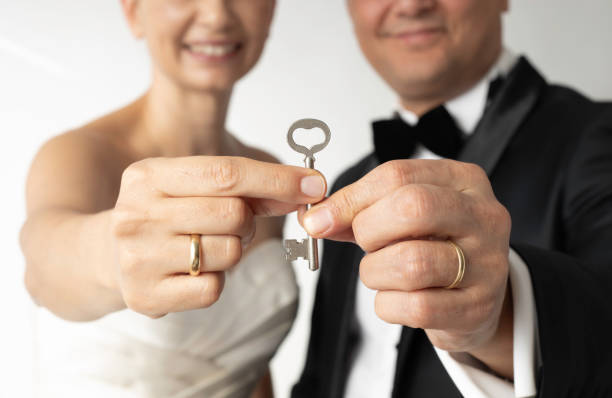 The bride and groom are holding a heart shaped house key.