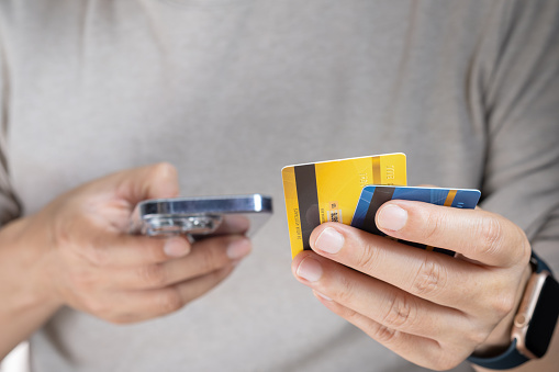 A man holds several credit cards and he uses a smartphone. To pay and pay for online products via credit card Finance and banking concept