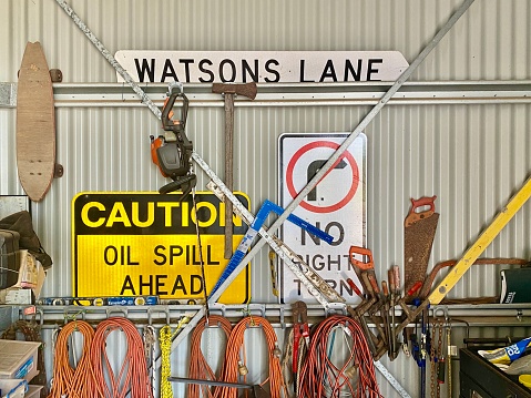 Horizontal still life of man's farm shed wall with tools, equipment, road signs, extension chords and supplies for rural living in country NSW Australia