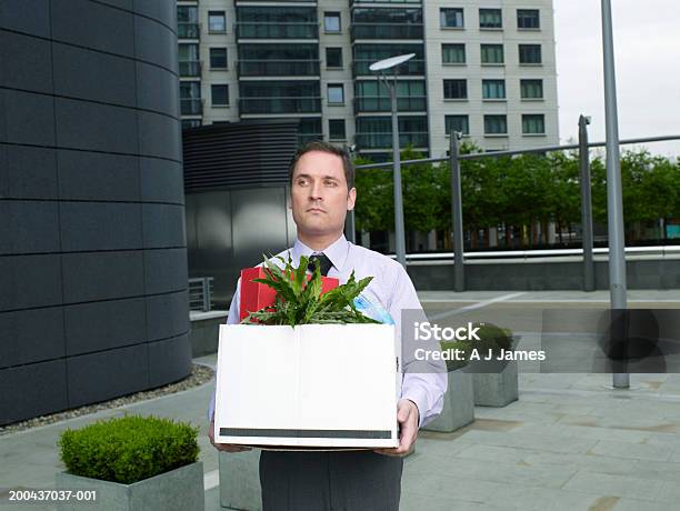 Businessman Carrying Box Containing Plant And Files On Street Stock Photo - Download Image Now