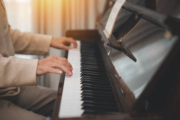 istock senior retirement man with eyeglasses learn to play piano at home 2004403263