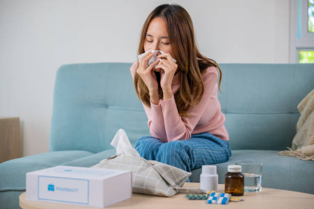 istock Asian young girl cold sick she sneeze with tissue paper on sofa 2004403789