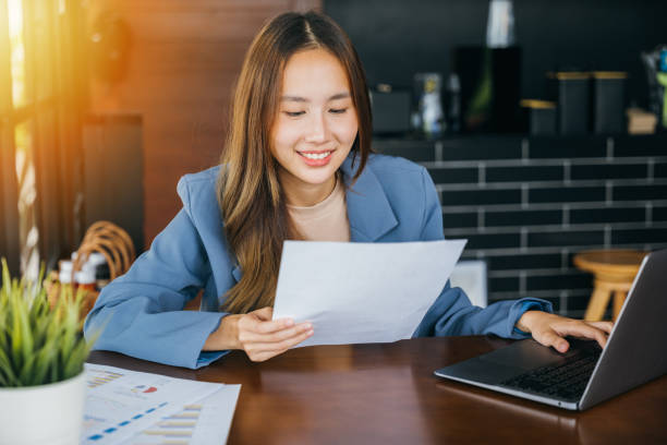 istock young business woman reading report document compare with laptop computer 2004403805
