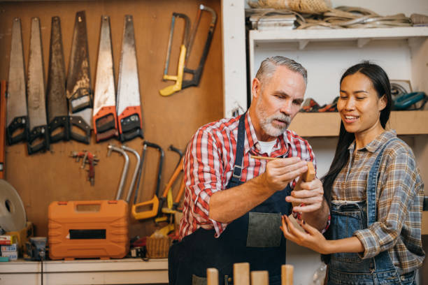 istock Craftsmen senior man teaching woman apprentice at woodshop 2004403857