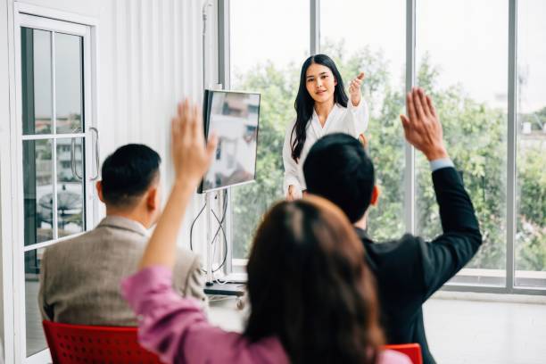 istock A seminar classroom hosts a large group actively engaging in the discussion, raising their hands. The answers are ready within this dynamic conference audience. 2004409783