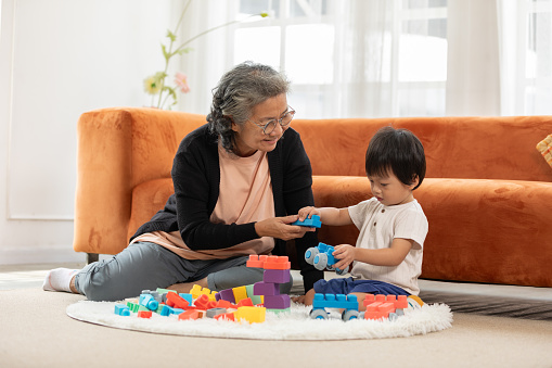 Heartwarming scene as baby toddler enthusiastically plays with stacking blocks, bringing joy to the faces of grandmother in delightful family bonding moment. love and good moment concept