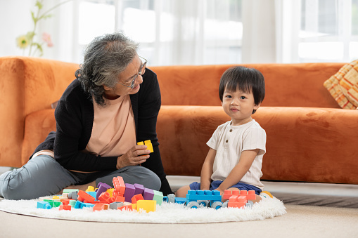 Heartwarming scene as baby toddler enthusiastically plays with stacking blocks, bringing joy to the faces of grandmother in delightful family bonding moment. love and good moment concept