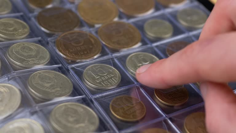 Collector Putting an Old Collectible Coin of the USSR into the Cell of Album