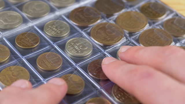 Hands Touching the Pages of a Numismatic Album with Old Soviet Ussr Coins