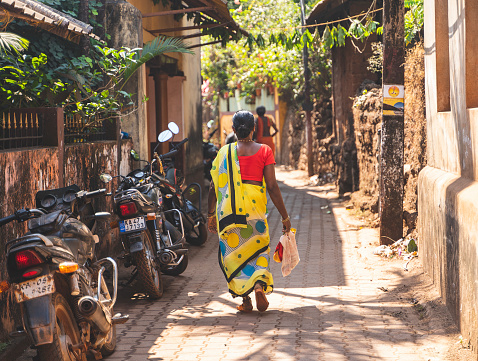 Gokarna, India - February 21, 2023 - Morning in Gokarna, rear view of Indian woman in sari walking down the street.