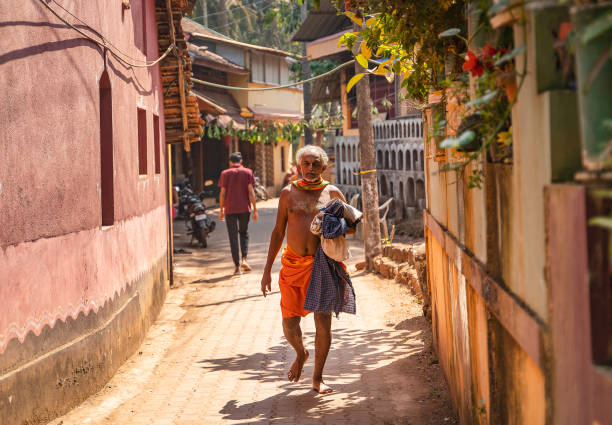 matin à gokarna, un homme vêtu d’un pagne orange marchant dans la rue - india brahmin hinduism tourism photos et images de collection