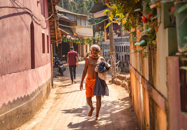 ゴカルナの朝、オレンジ色のふんどし姿の男が通りを歩いている - indian ethnicity traditional culture architecture karnataka ストックフォトと画像