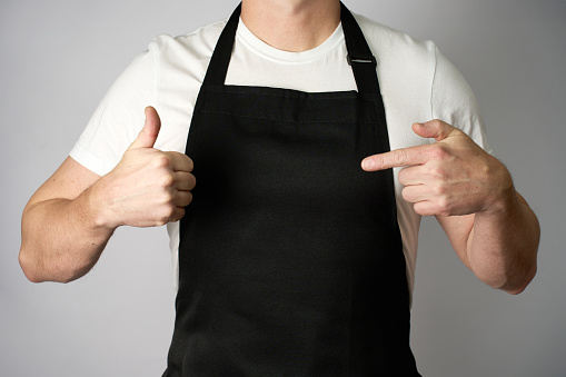 Male chef wearing apron and pointing with hand, close-up, standing on a white background. Can be used for restaurant menu