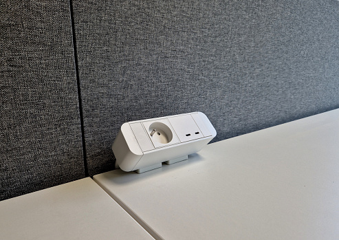 desk socket on the work table with 220, 230 volt and 12V usb. gray openspace partitions made of felt carpet. white worktop. office ergonomic environment.slot, 220v, 230v, notebook, partition wall,