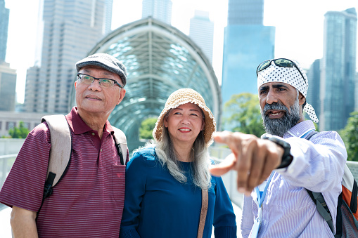 A private Sikh tour guide and two senior Asian traveler walking through the famous Saloma Bridge landmark in the city of Kuala Lumpur, Malaysia.