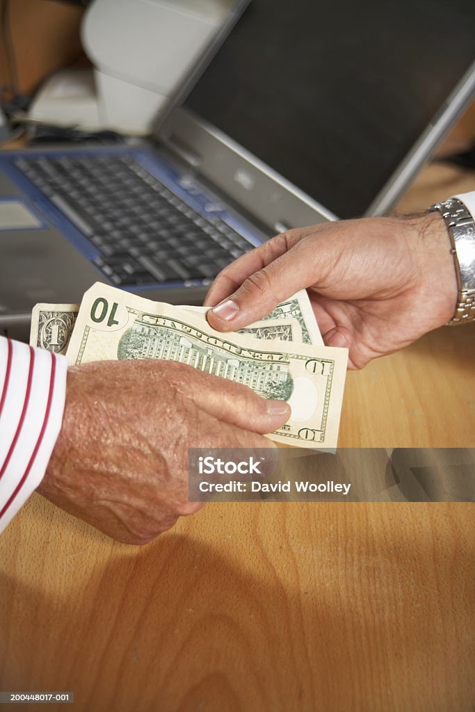 Senior man handing another man banknotes, close-up  30-39 Years Stock Photo