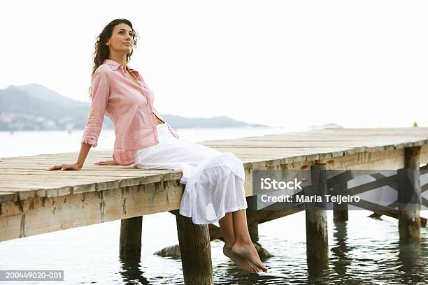 Young Woman Relaxing On Jetty Stock Photo - Download Image Now - One Woman Only, Sitting, Skirt