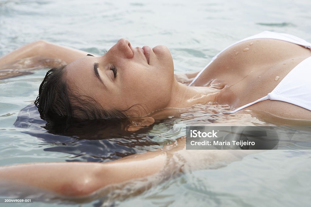 Young woman floating in sea, eyes closed, close-up  One Woman Only Stock Photo