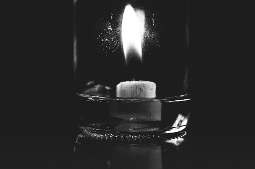 a candle burns in a jar, candle light in the dark, candle light shines in the darkness