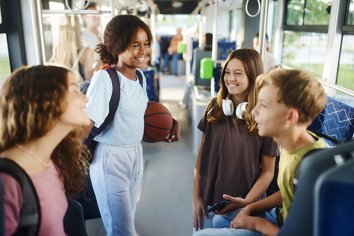 Group of happy students communicating while traveling to school by public transportation.