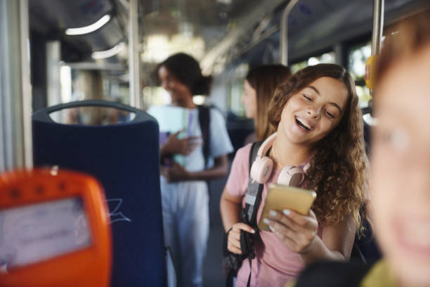 istock Happy schoolgirl using cell phone while traveling to school in a bus. 2004552523