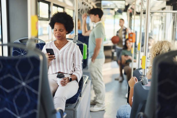 istock Smiling black woman using cell phone in a public transport. 2004558898