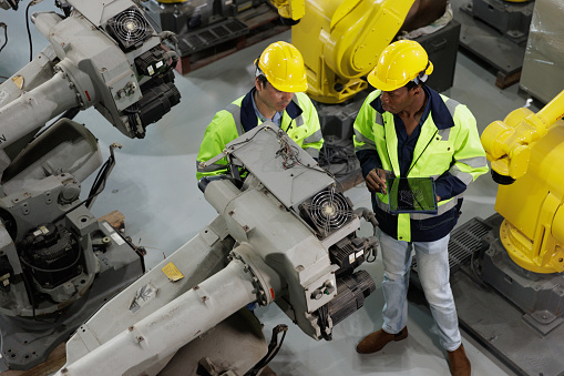 Two Engineer checking robot arm together in factory