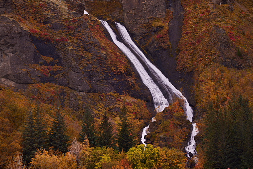 Waterfall falling down the mountain during autumn day in Iceland.
