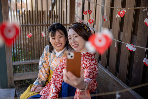 Female friends in Kimono / Hakama taking stifle picture on street in traditional Japanese town
