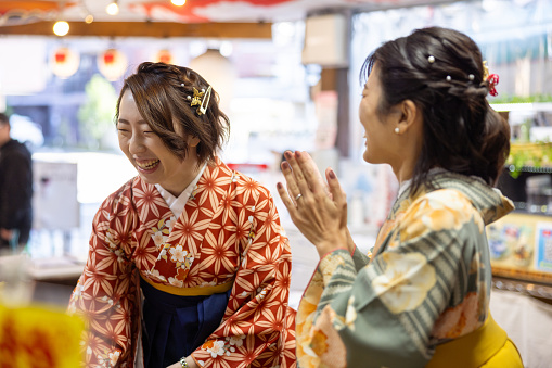 Female friends in Kimono / Hakama playing in shooting booth in traditional Japanese town