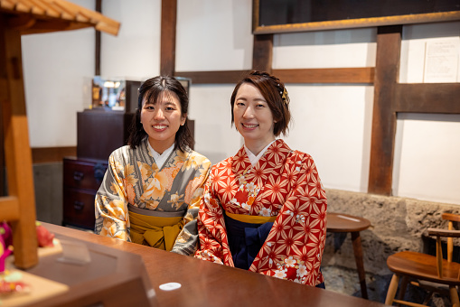 Female friends in Kimono / Hakama sitting on bench in cafe