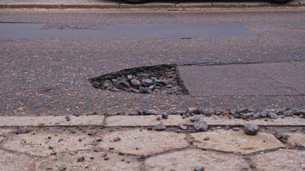 istock Deep Pothole in Asphalt Road Surface Caused by Erosion during Winter Season 2004586713