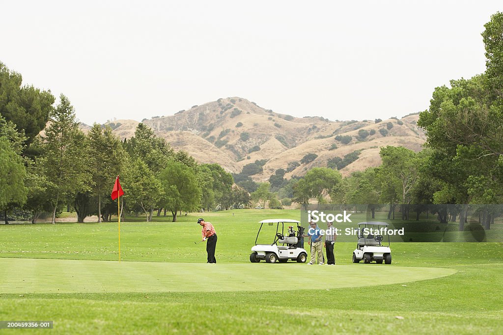 Мужчины, играть в гольф, тележки в зеленой - Стоковые фото Гольф роялти-фри