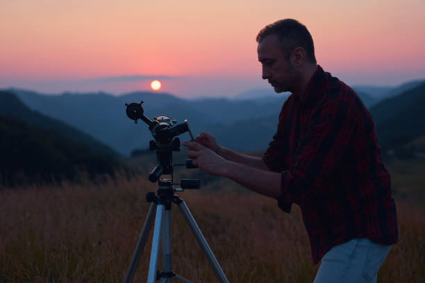 istock Astronomer looking at the sun with a telescope and using a cellphone. 2004608929
